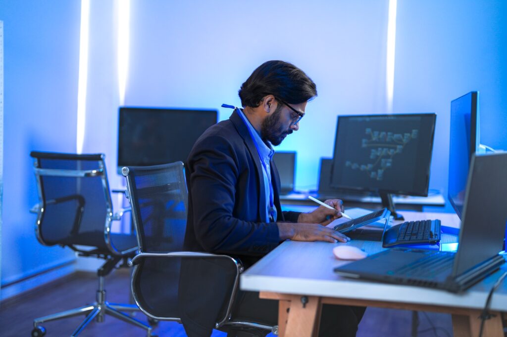 Focused Indian male AI developer coding a complex machine learning algorithm late