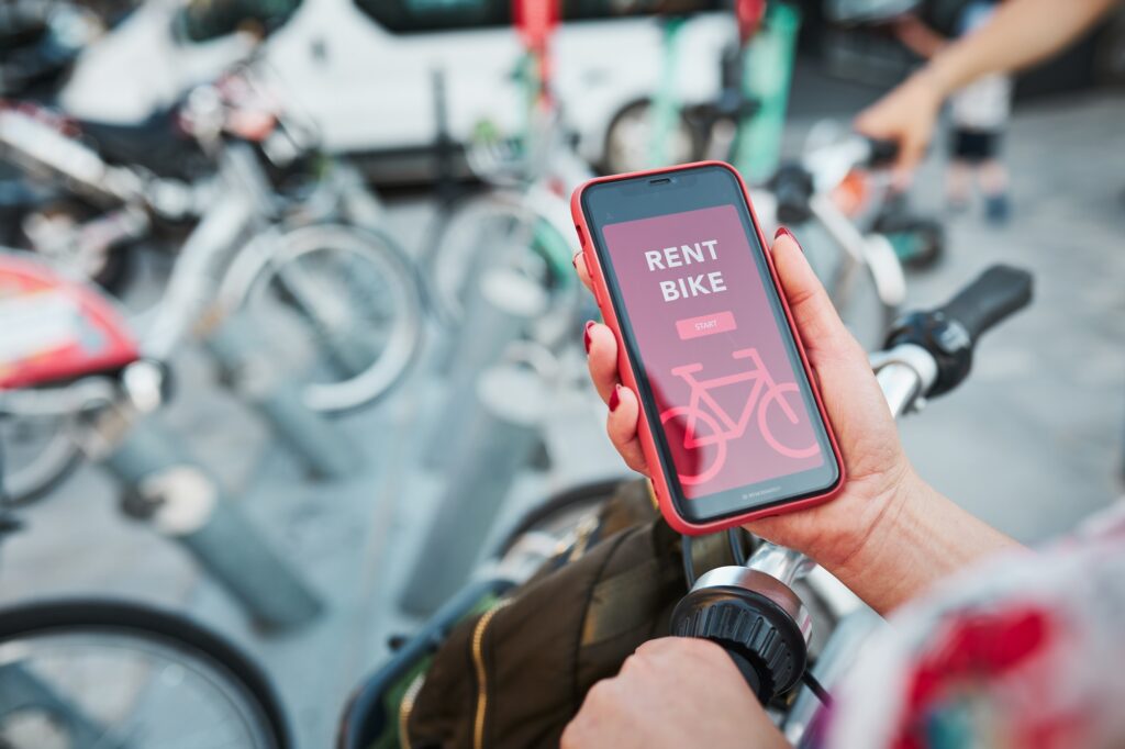 Renting bike using rental app on mobile phone. Using bike sharing city service. Mobile app